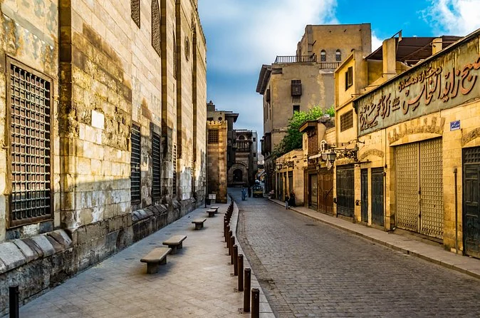A quiet stone lane in Islamic Cairo with old facades and closed shutters in morning light