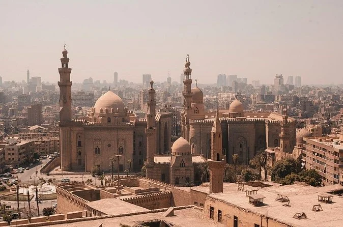 A hazy view over the domes and minarets of Islamic Cairo with Sultan Hassan in front