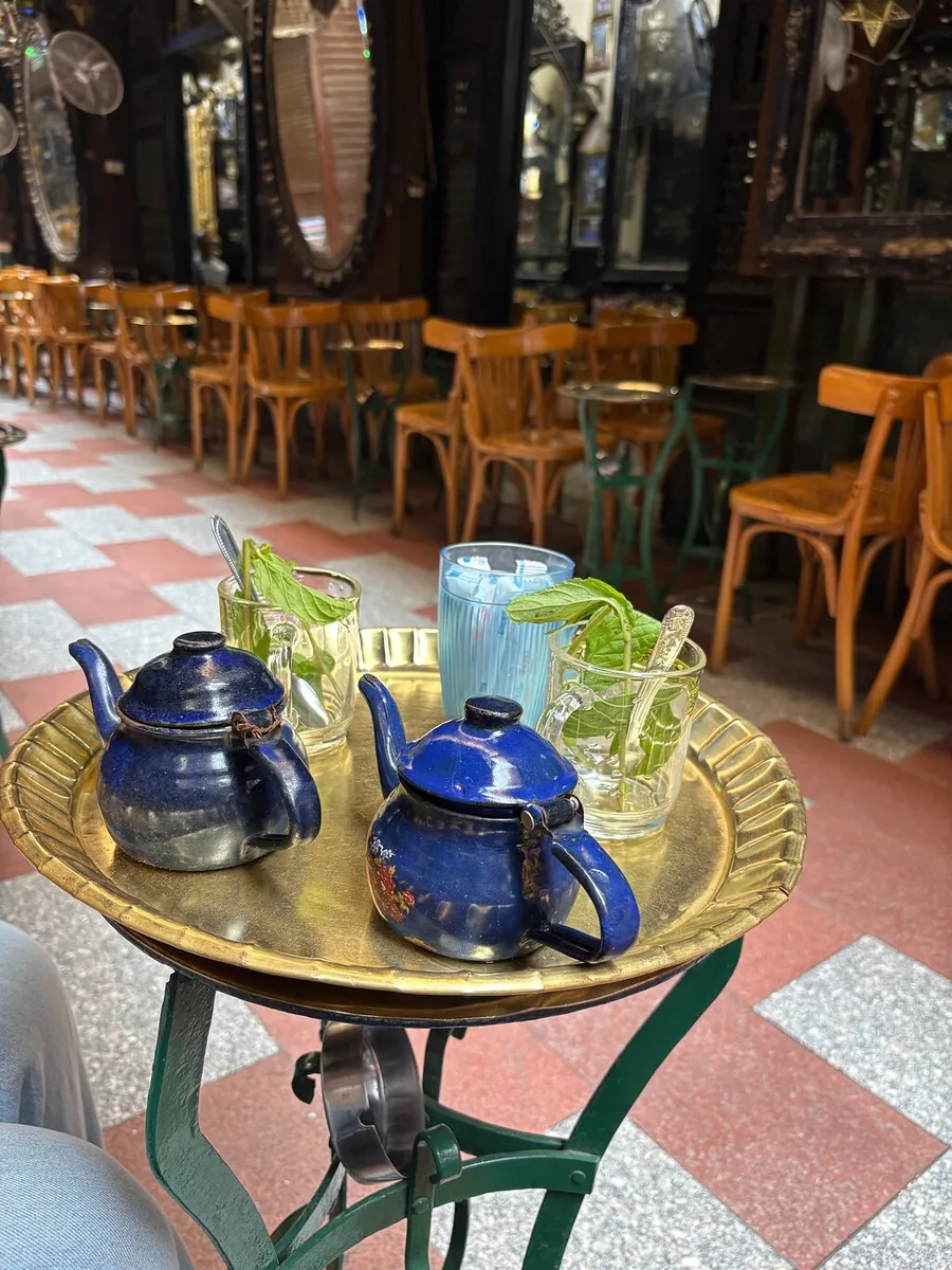 Two blue teapots and glasses on a brass tray at a café table in Khan el-Khalili