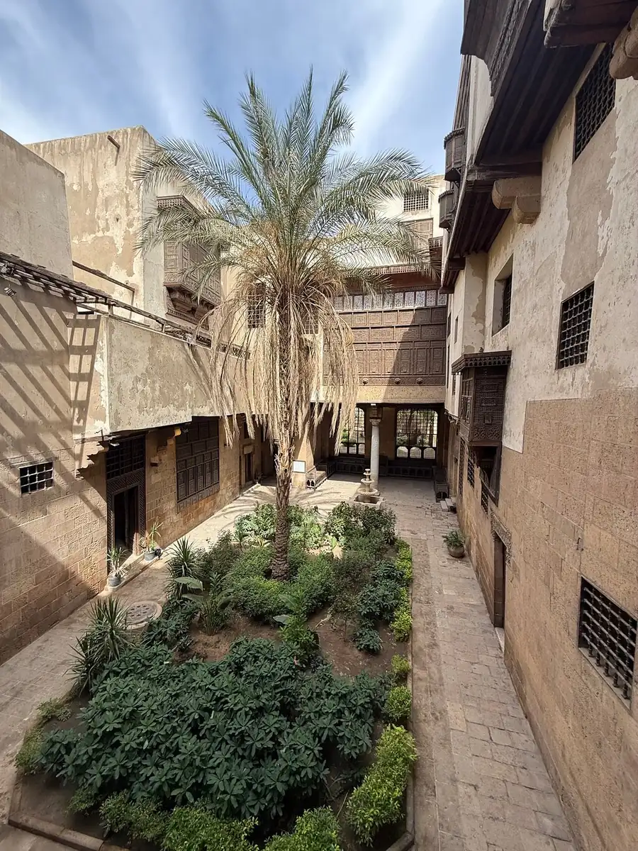 The garden courtyard of Bayt al-Suhaymi with a palm tree and wooden screened windows